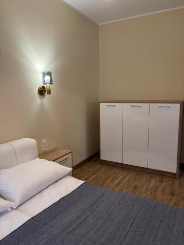 a bedroom with a bed with white sheets and cabinets at Czarna Perła Hel in Hel