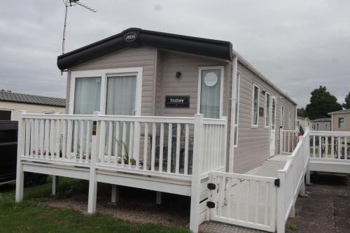 a tiny house with a white railing and a porch at Dennys Holiday Home Pet Free in Blackpool
