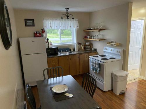 eine Küche mit einem Tisch und einem weißen Kühlschrank in der Unterkunft Down Home Accommodations in Rocky Harbour