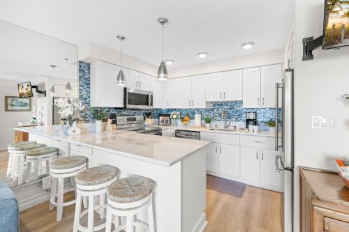a kitchen with white cabinets and bar stools at Lahaina Roads 407 in Lahaina