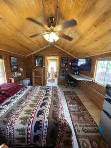 a bedroom with a large bed with a ceiling fan at Alaska Log Cabins on the Pond in Clear Creek Park