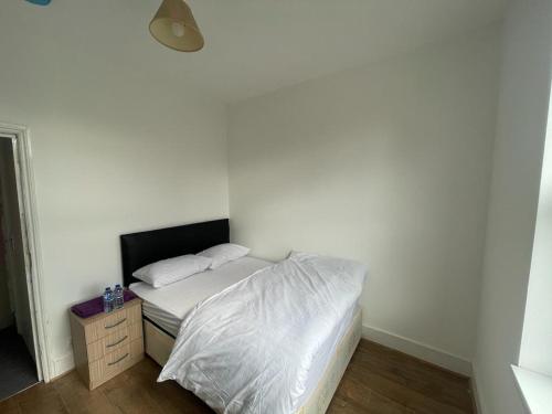 a bedroom with a bed with white sheets and a nightstand at GNDJ Hotel Skegness in Skegness