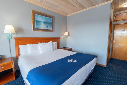a hotel room with a large bed with a blue blanket at Fisherman's Wharf Inn in Boothbay Harbor