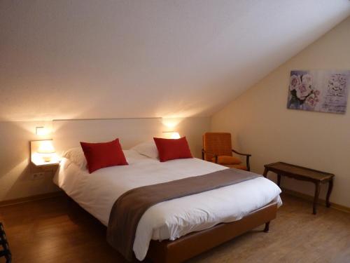a bedroom with a large bed with two red pillows at Logis Hôtel Notre-Dame - restaurant ouvert midi et soir sauf dimanche soir in Danne-et-Quatre-Vents