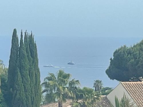 un navire de croisière dans l'eau avec des arbres dans l'établissement Villa avec piscine vue sur la mer, à Cannes