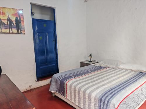 a bedroom with a bed and a blue door at My Friend Surf Hostal in Trujillo