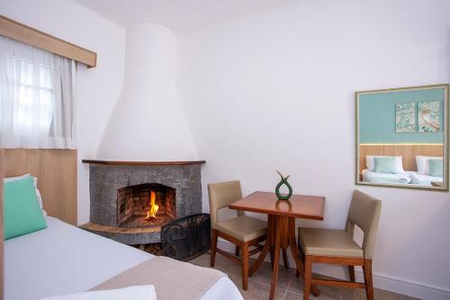 a bedroom with a fireplace and a table and chairs at Pousada das Videiras boutique in Monte Verde