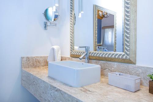 a bathroom with a white sink and a mirror at Pousada das Videiras boutique in Monte Verde