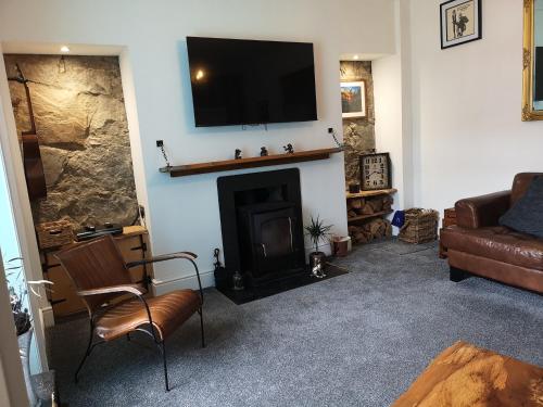 a living room with a fireplace with a television on the wall at Friars Shott Cottage in Inverness