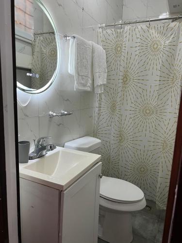 a bathroom with a sink and a toilet and a mirror at Azure Villa Suites Apart Hotel in Limbe