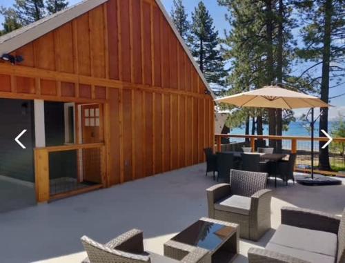 キングスビーチにある#9 Lakeside Location Beach Access View BalconyDogの椅子とテーブルと傘のある木造の建物