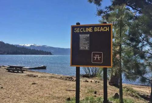 a sign on a beach near a body of water at #10 Lakeside Great Location Beach Access Dogs ok in Kings Beach