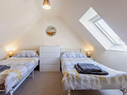 een zolderslaapkamer met twee bedden en een raam bij 2 Bed in Bude 82163 in Bude