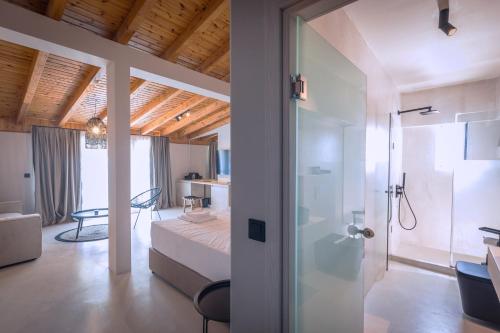 a bedroom with a bed and a glass door leading to a bathroom at Laki Beach Hotel in Nea Plagia