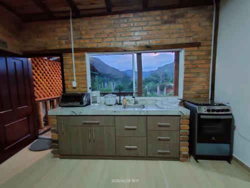 a kitchen with a sink and a large window at Acogedora Casa de Campo Vilcabamba in Loja