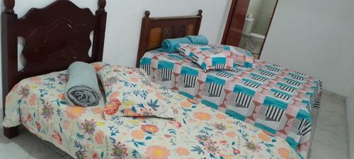 a bed with a comforter and pillows on it at Suíte Tripla Bougainville 2 in Areia