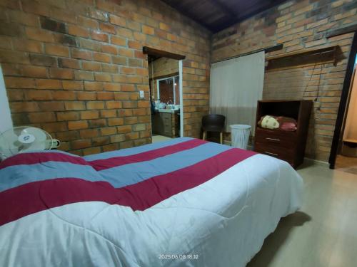a bedroom with a large bed in a brick wall at Acogedora Casa de Campo Vilcabamba in Loja