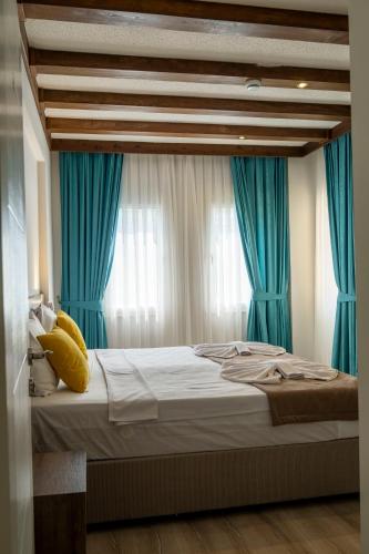 a bedroom with a large bed with blue curtains at Güneş Boutique Hotel - Oludeniz in Oludeniz
