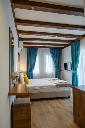 a bedroom with a large bed with blue curtains at Güneş Boutique Hotel - Oludeniz in Oludeniz