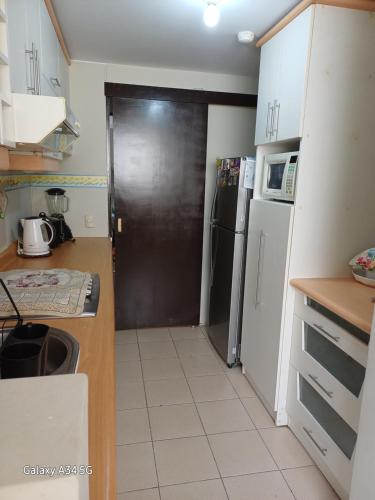 une cuisine avec une porte noire et un réfrigérateur dans l'établissement Cómodo departamento familiar, à Lima