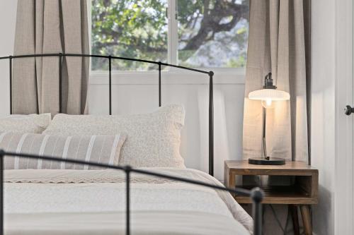 a bedroom with a bed with a lamp and a window at The River House in Three Rivers