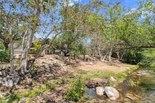 a yard with trees and a stream in front of a house at The River House in Three Rivers