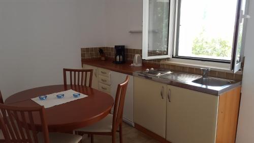 a kitchen with a table and a sink and a table and chairs at Apartments Iličić in Supetar