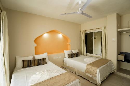 a bedroom with two beds and a ceiling fan at Gran SAHARA in Playa del Carmen