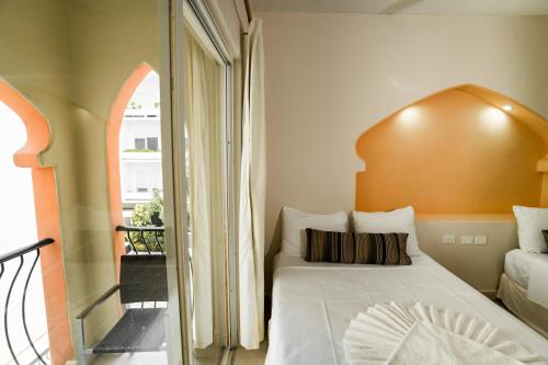 a bedroom with a white bed and a balcony at Gran SAHARA in Playa del Carmen