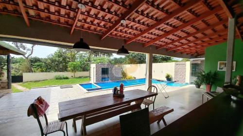 une terrasse avec une table et des chaises en bois ainsi qu'une piscine dans l'établissement Chácara Top, à Caldas Novas