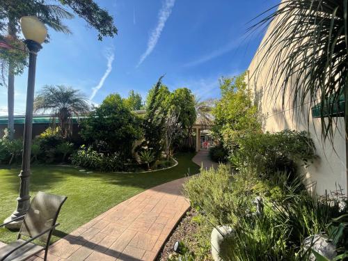 a garden with a brick walkway and a street light at Hotel Pacific Garden in Gardena