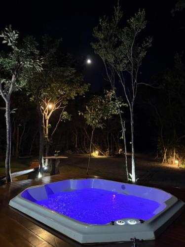 a jacuzzi tub with purple lights in a yard at night at Casa.dovale3 in Caeté-Açu