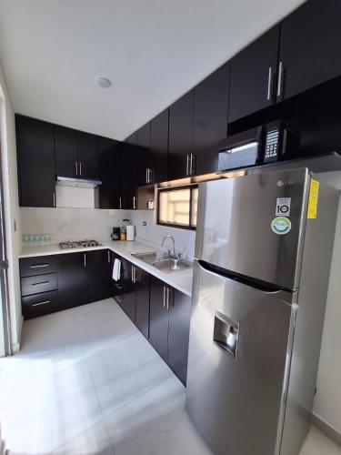 a kitchen with black cabinets and a stainless steel refrigerator at Casa Coruña in Durango in Durango
