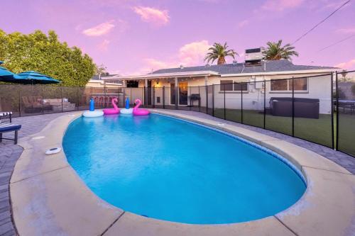 a swimming pool with pink inflatables in front of a house at Chic Scottsdale Escape with Pool in Scottsdale