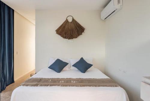 普拉亚卡门GLASS JUNGLE VILLA with amazing green views -10 min DT的卧室里有一张白色的床和蓝色的枕头