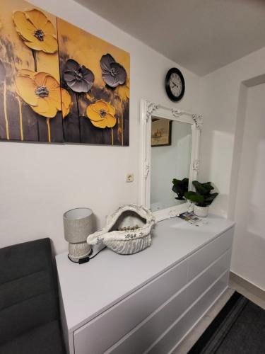 a dresser in a room with a mirror and a clock at Apartmani i sobe Mara in Rab