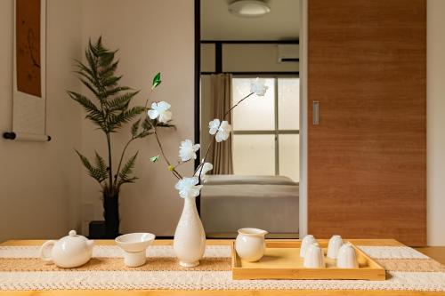 a vase with white flowers in it on a table at ELIM Private Vacation Home near Umeda Japanese-style Entire 3BR House with Tea Room in Osaka