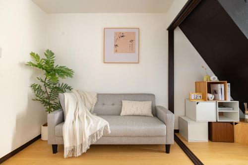a living room with a gray couch and a plant at ELIM Private Vacation Home near Umeda Japanese-style Entire 3BR House with Tea Room in Osaka