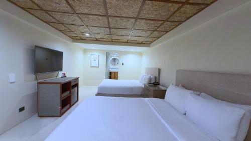 a bedroom with two beds and a flat screen tv at Whiterock Beach Hotel and Waterpark in Subic