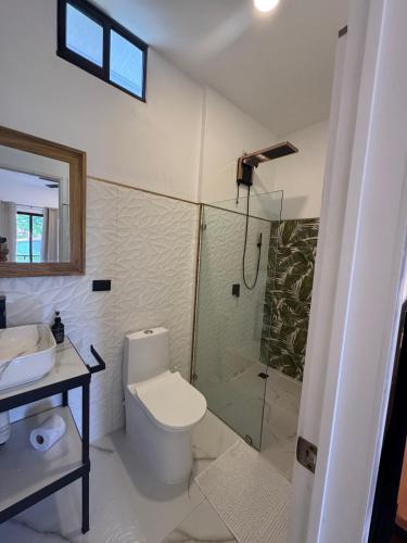 a bathroom with a toilet and a glass shower at Villa Esmeralda in Uvita