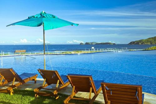 a group of chairs and an umbrella next to the ocean at Búzios Beach Resort Apartamento Luxo Home Premium 2 in Búzios