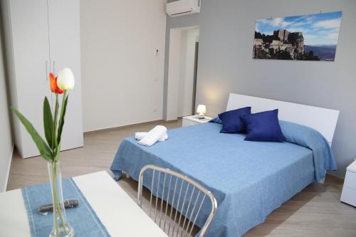 a bedroom with a blue bed and a vase with a flower at La Bussola in Trapani