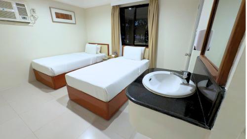 a hotel room with two beds and a sink at Whiterock Beach Hotel and Waterpark in Subic