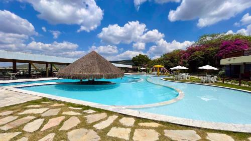 a swimming pool with a straw umbrella and chairs at Flat 8b Monte Castelo , gravatá in Sairé