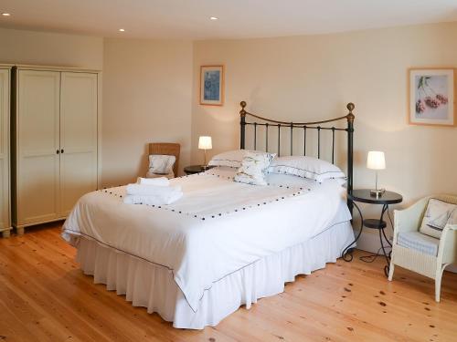 a bedroom with a large white bed and a chair at Tides Reach in Fowey