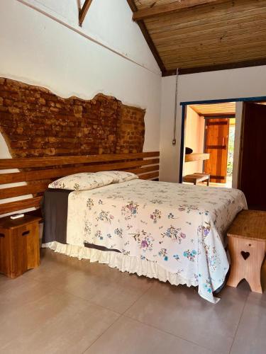 a bedroom with a bed and a brick wall at Fazenda Brotas SP in Brotas