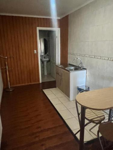 a kitchen with a sink and a toilet and a table at Hotel Plaza Los Leones in Curanilahue