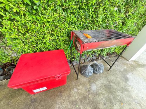 a red barbecue grill sitting next to a bush at Medina Private Pool Villa-บางแสน in Ban Puk (1)