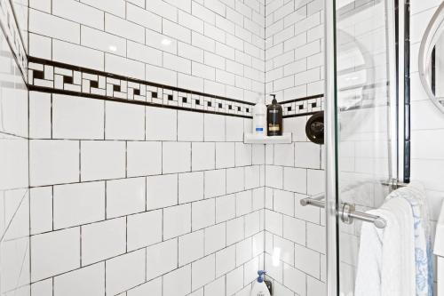 a white tiled shower with a bottle of wine at Tiny Cargo Home South in Tulare