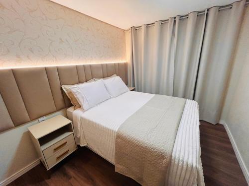 a small bedroom with a bed and a night stand at Cantinho de canela in Canela